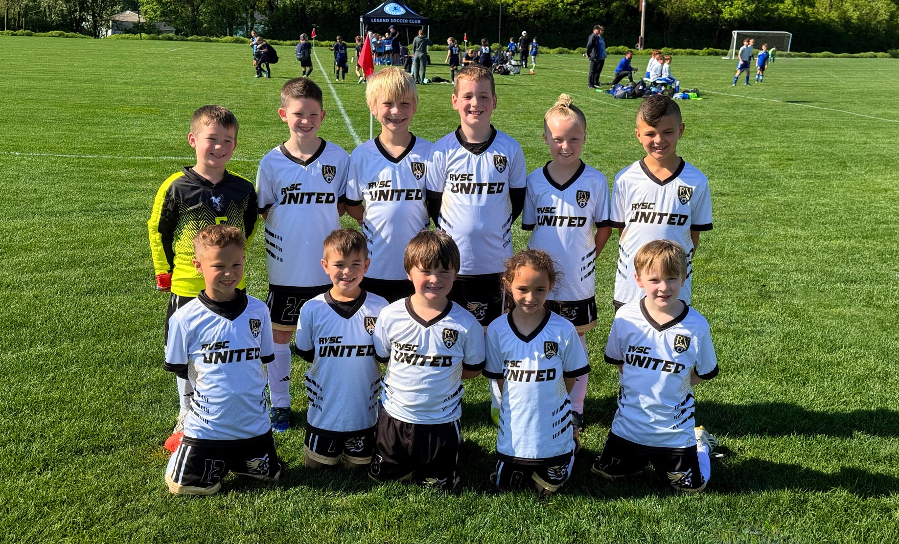 Children in sports uniforms posing on a grass field